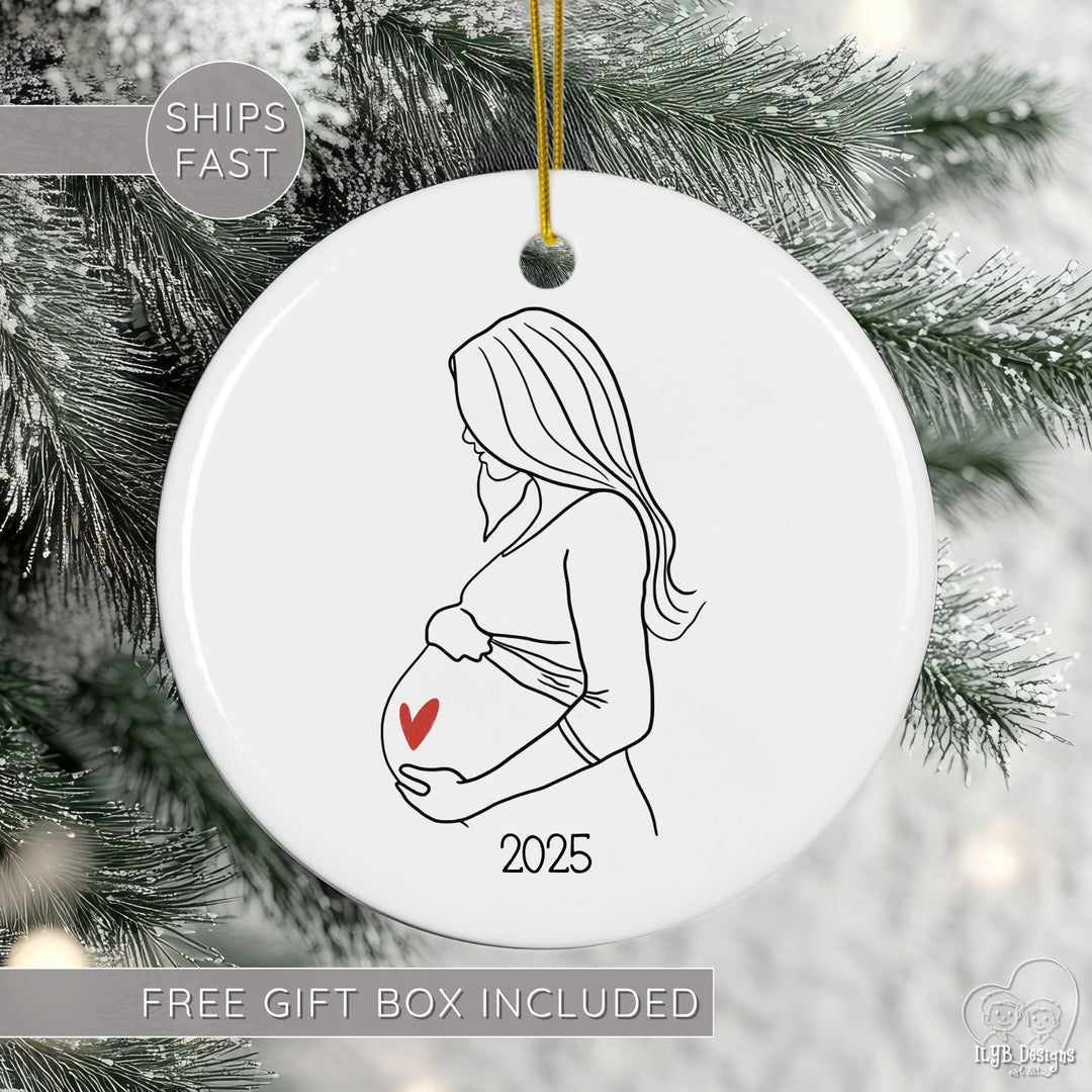 Decorative ornament with a pregnant woman silhouette and heart, hanging on a Christmas tree.