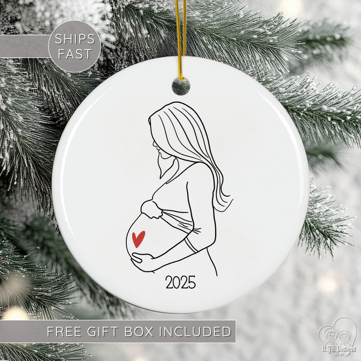Decorative ornament with a pregnant woman silhouette and heart, hanging on a Christmas tree.