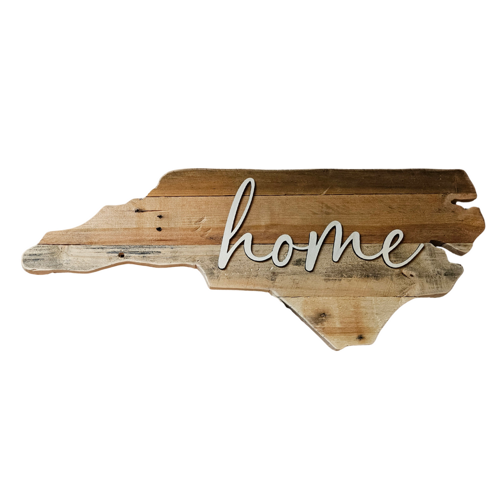 Pallet sign shaped like state of North Carolina with 3D 'home' written in script font on it against a white background