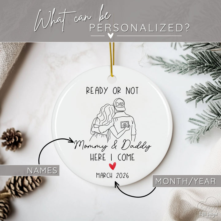 Graphic showing what part of Christmas ornament can be personalized. Arrows pointing to the names and month-year that can be personalized for a round white personalized ceramic Christmas pregnancy announcement ornament featuring a black and white line drawing of a man and woman holding a sonogram, with the dad wearing a “DAD” hat. The playful phrase, “Ready or not, here I come Mommy & Daddy” and a red heart accent make it a touching keepsake ornament.