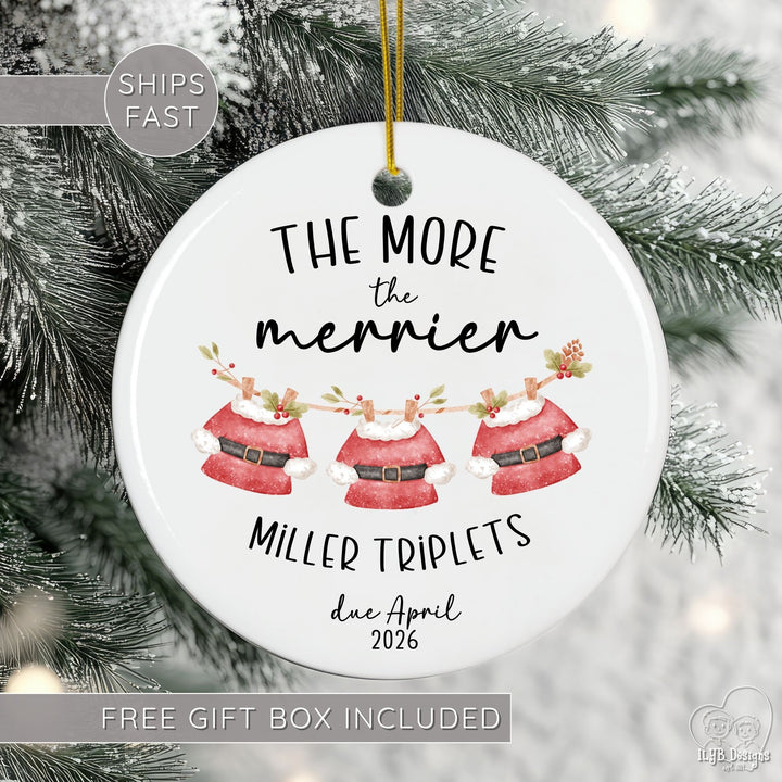 Personalized ceramic Christmas ornament for mom of multiples pregnancy featuring the festive phrase āThe More the Merrierā, your custom name, number of babies (twins, triplets, quadruplets, or more), and month/year due date. Designed with modern black script and print lettering and a cute watercolor clothesline with Santa clothes hanging for each baby, this pregnancy announcement ornament is perfect for twin pregnancy reveals, triplet announcements, or any multiples baby announcement.