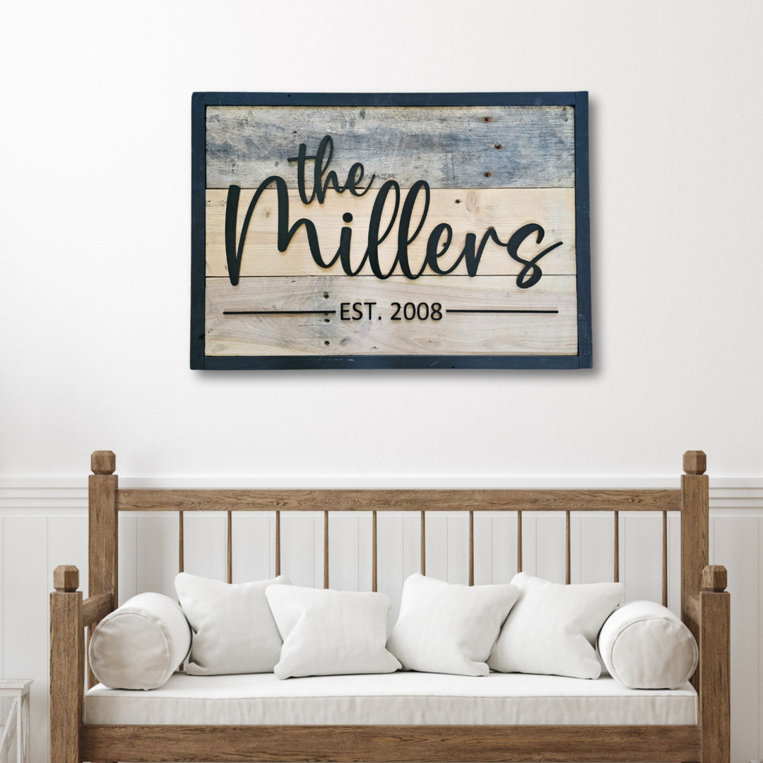Decorative pallet wall sign with black frame and 'the Millers est. 2008' on a white wall above a wooden bench.