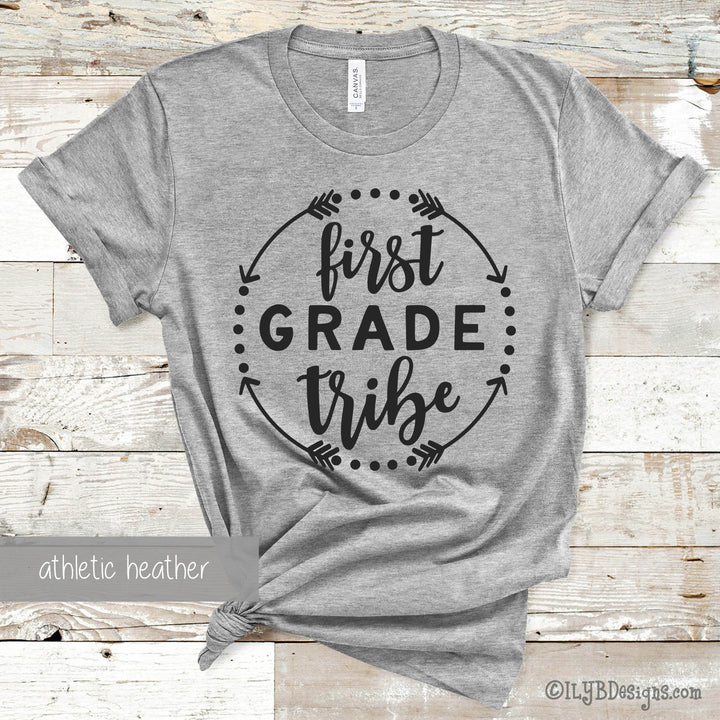 Gray t-shirt with 'first grade tribe' black text in a circle made of arrows and dots.