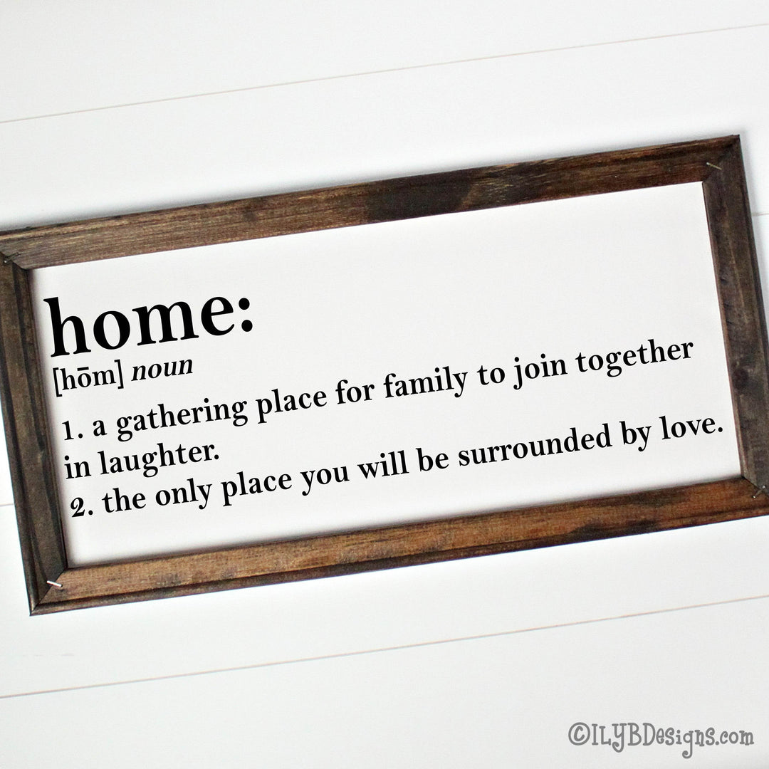 Wooden-framed canvas sign with definition of 'home: A gathering place for family to join together in laughter. The only place you will be surrounded by love.' in black text.