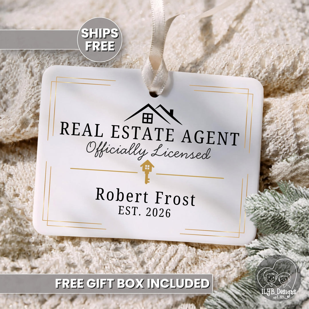 A personalized white hanging ornament with a ribbon loop, printed with 'REAL ESTATE AGENT Officially Licensed', 'Robert Frost', and 'EST. 2026', styled on a beige knit blanket with a 'SHIPS FREE' badge and 'FREE GIFT BOX INCLUDED' text.