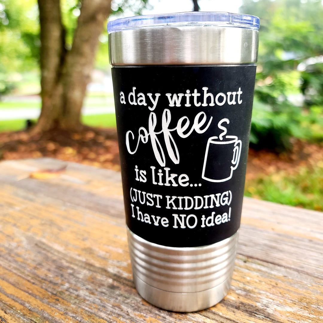 Black laser engraved 20 oz Polar Camel stainless steel tumbler with clear lid, black silicone sleeve with white engraving that says "a day without coffee is like...just kidding I have no idea!