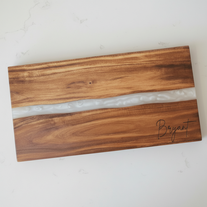 Wooden cutting board with a white resin inlay and the last name 'Bryant' engraved in the bottom right corner.