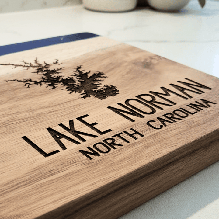 Close up of acacia wood cutting board with 'Lake Norman North Carolina' engraving in bottom right corner on a light background