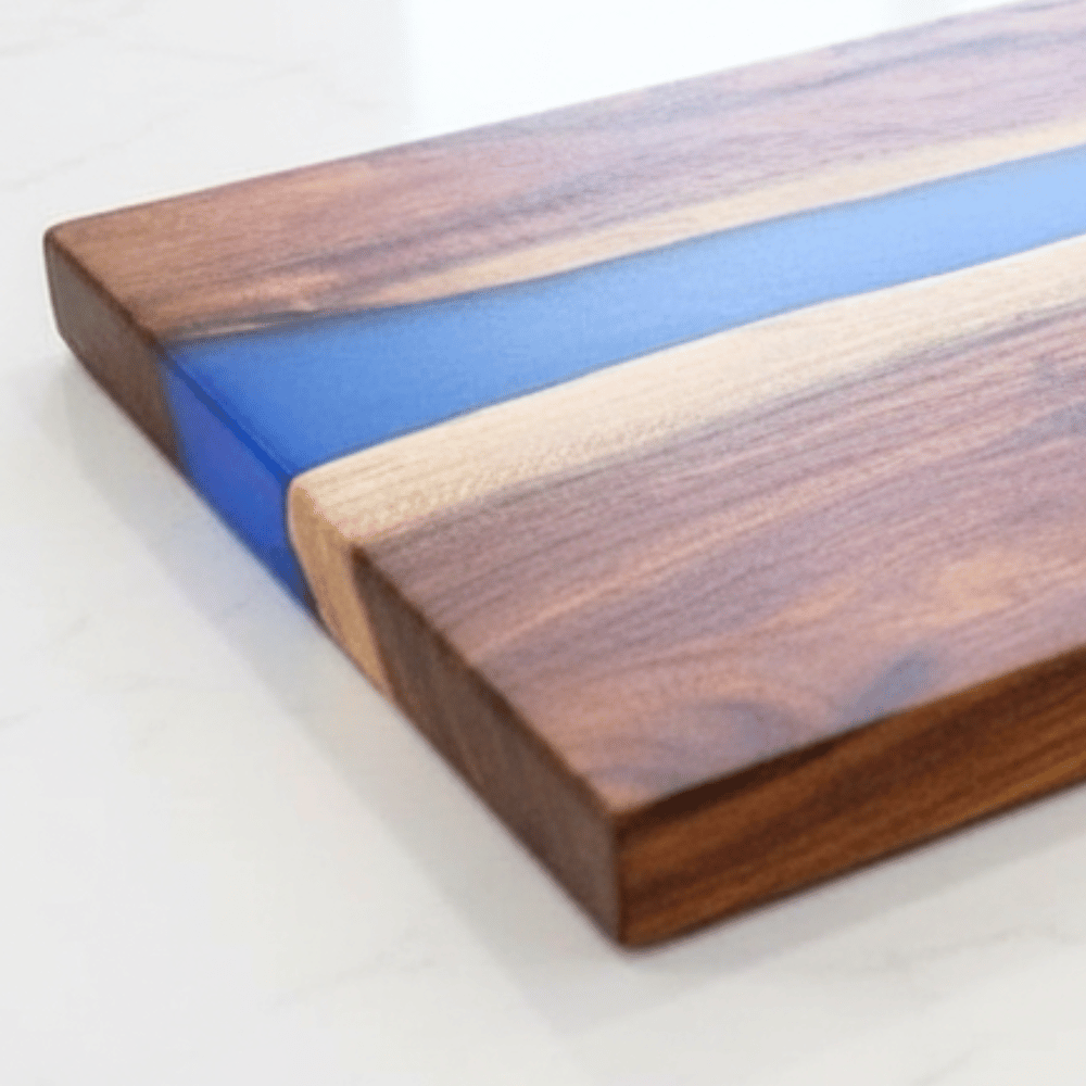 Wooden cutting board with blue resin inlay on a white background