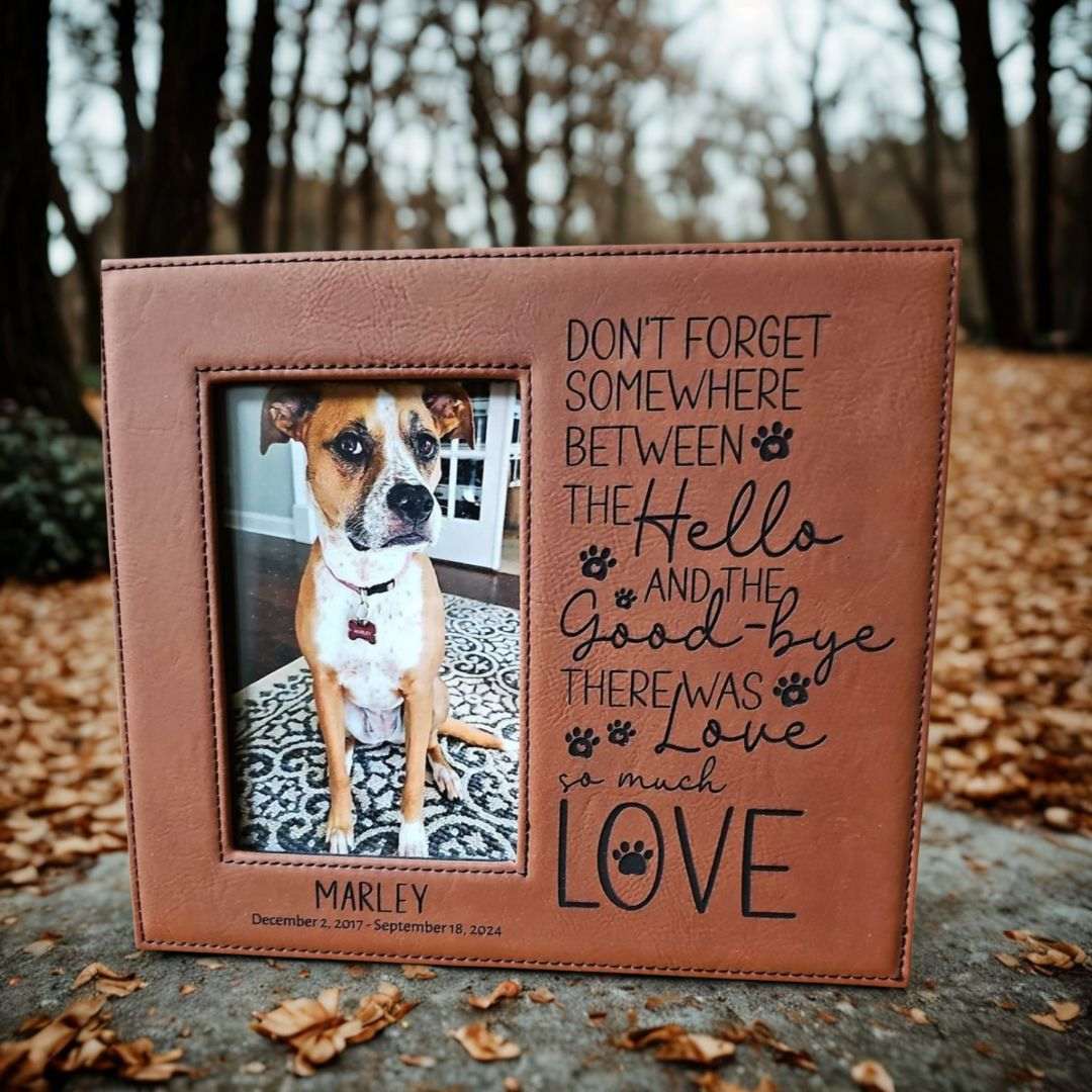 Brown leather photo frame with a dog picture and engraved text in an outdoor setting.