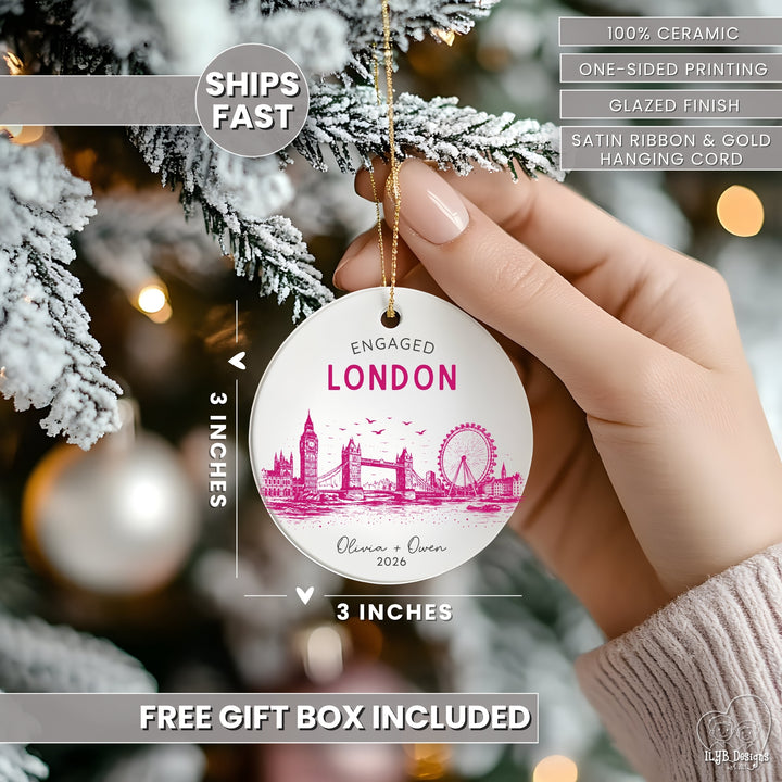 A hand holds a round ceramic Christmas ornament featuring a pink London skyline and the words &