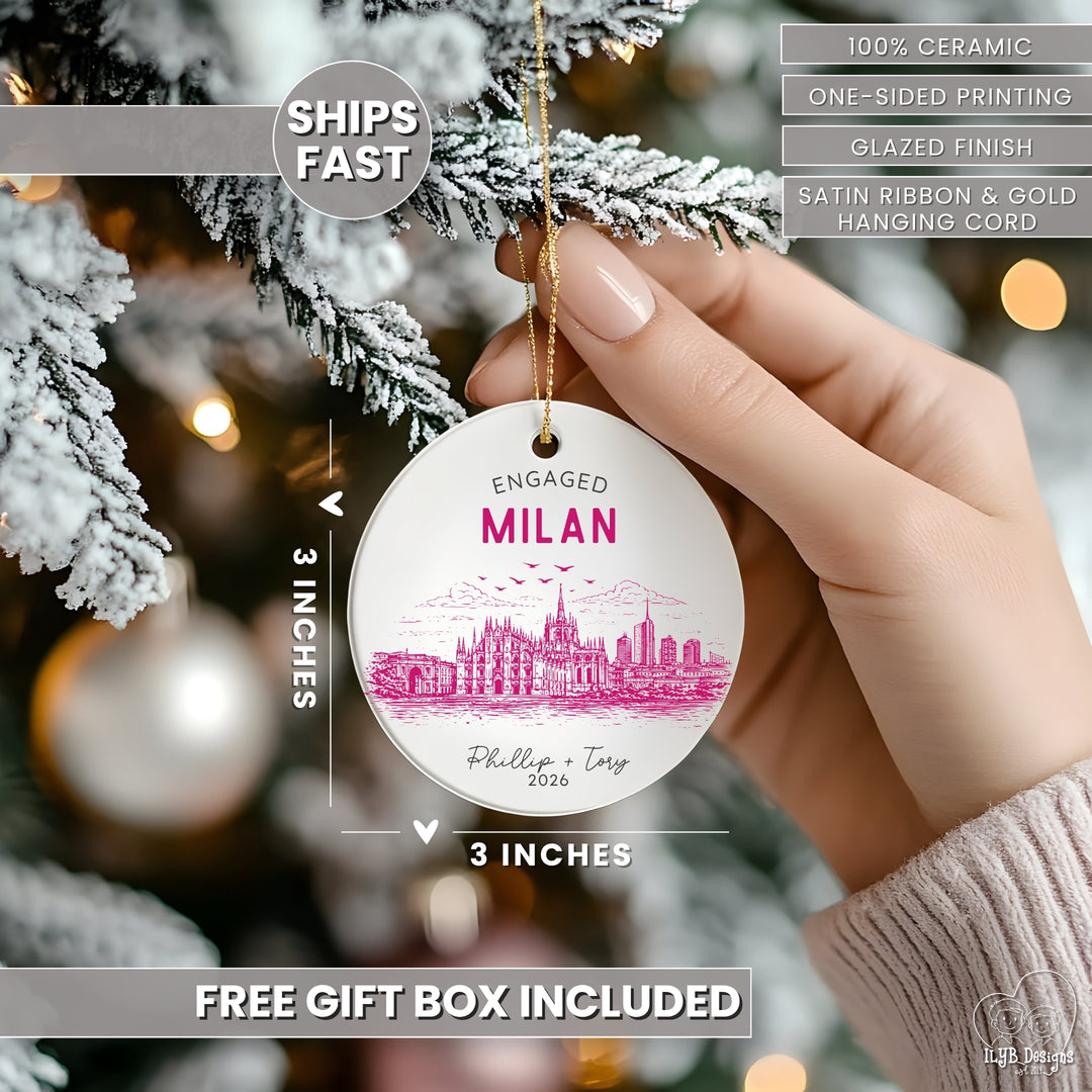 A hand holds a round white ceramic Christmas ornament featuring a pink city skyline and the text &
