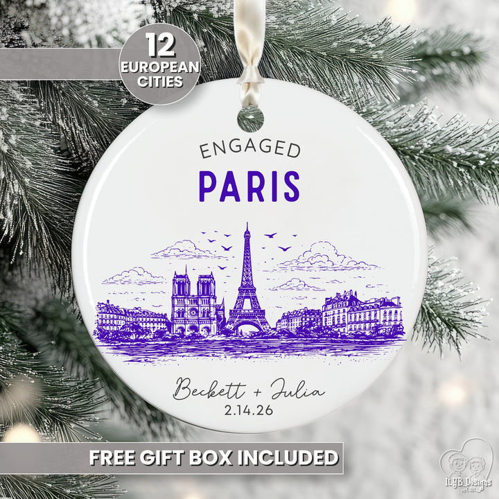 A round white ceramic Christmas ornament featuring a purple illustrated Eiffel Tower and Paris skyline with the text &