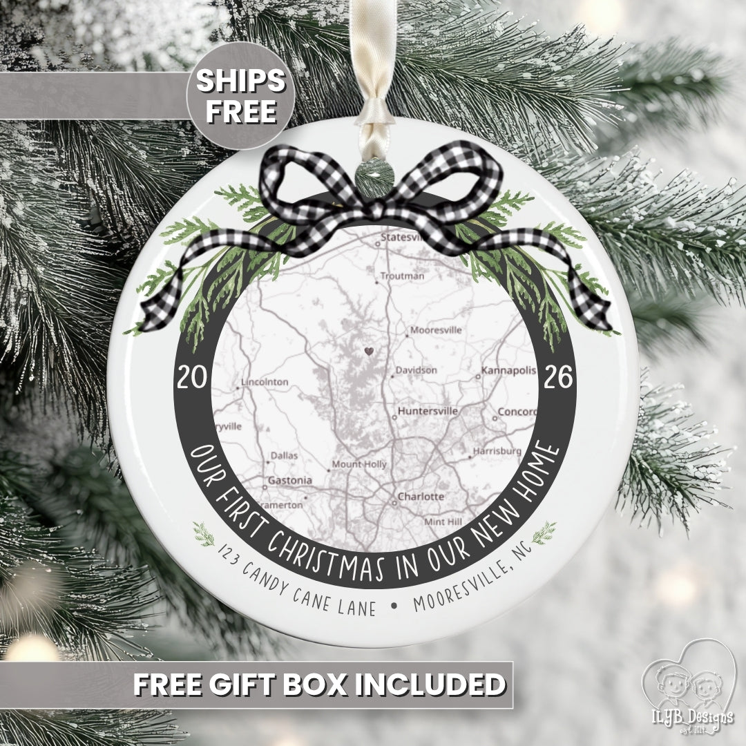 Personalized round Christmas ornament hanging on a snowy evergreen tree. The ornament features a printed map of Mooreville, NC, with the text 'Our First Christmas in Our New Home' and a black-and-white gingham ribbon bow at the top.