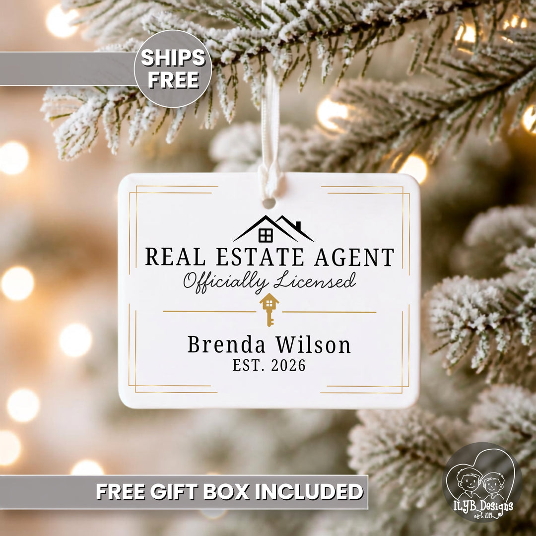 A personalized white rectangle ceramic ornament hanging from a snowy Christmas tree branch with warm bokeh lights in the background. The ornament reads &
