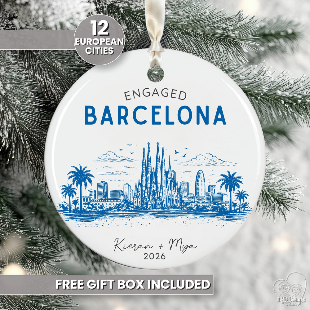 A round white ceramic Christmas ornament featuring a blue illustrated Barcelona skyline with the text 'ENGAGED BARCELONA' and personalized names/date, hanging against snowy tree branches. Promotional text overlays mention 12 European cities and free gift box included.