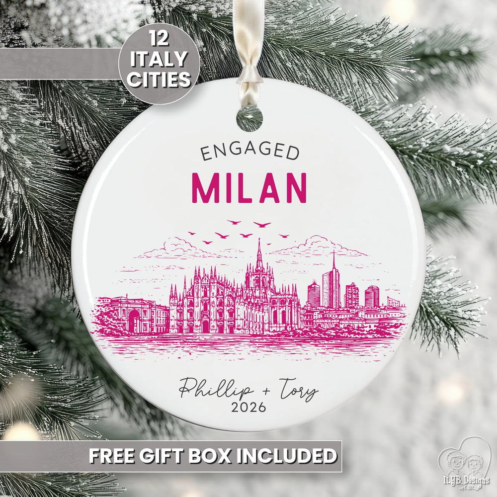 A round white ceramic Christmas ornament featuring a pink line art illustration of Milan, Italy, with the text 'ENGAGED MILAN' and personalized names/date. The ornament hangs from a white ribbon against a snowy Christmas tree background, with promotional text overlays that say '12 Italy Cities' and 'free gift box included'.