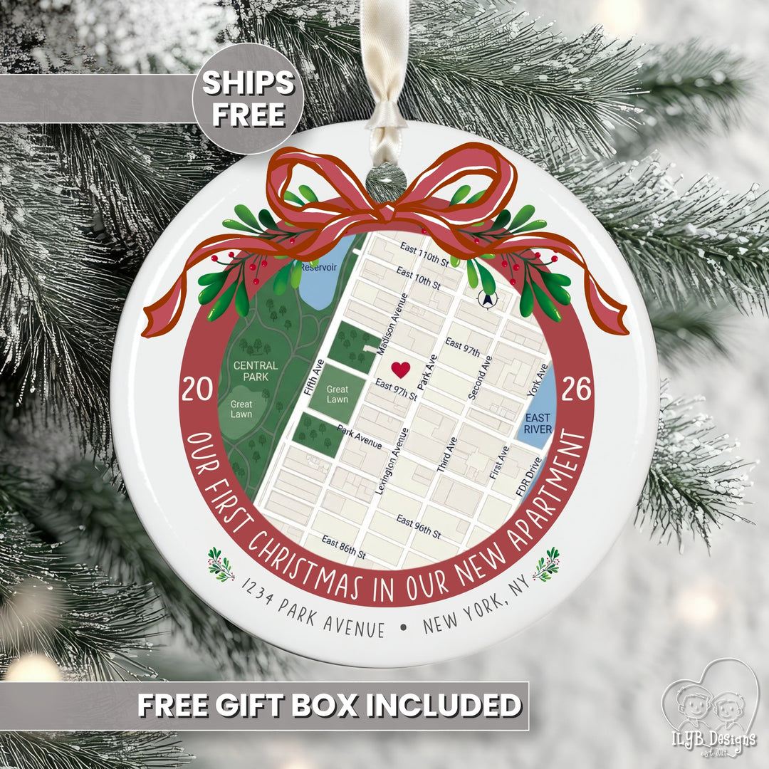 Personalized round Christmas ornament featuring a street map of a new apartment in New York City, wrapped in a red ribbon and green holly accents, hanging on a snowy Christmas tree. Text overlays read &