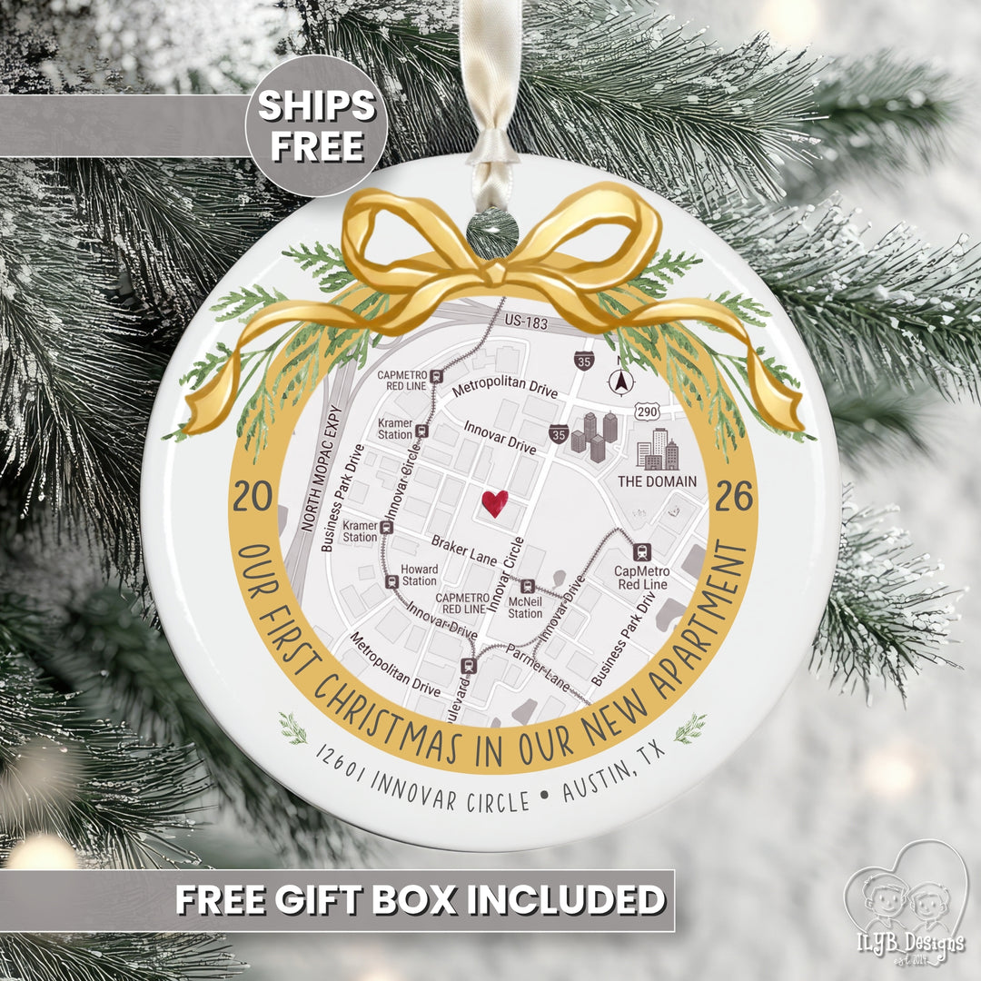 A round white Christmas ornament featuring a printed street map of a new apartment with a gold ribbon bow and green pine accents, hanging on a snowy tree. Text overlays read &