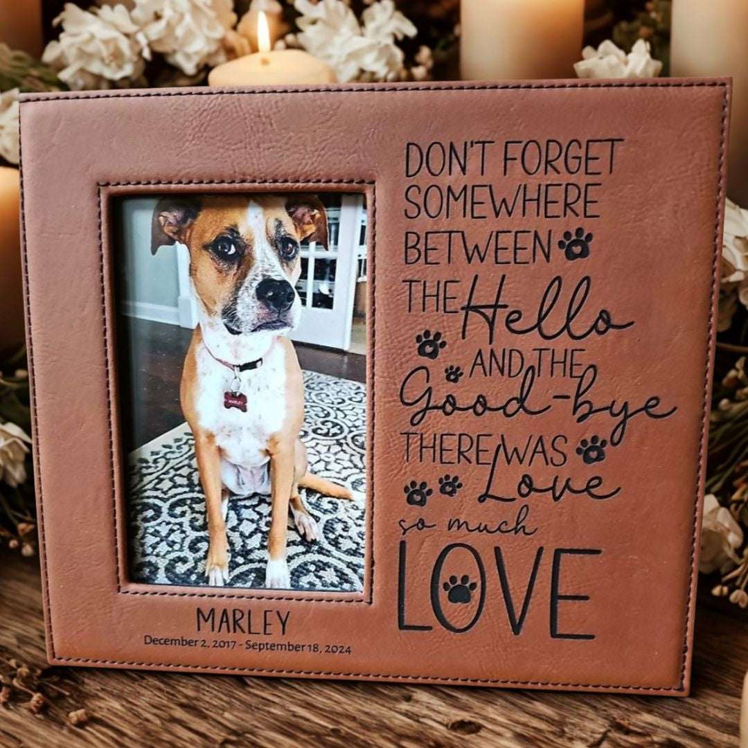 Brown leather photo frame with a dog picture and engraved text on a wooden surface.