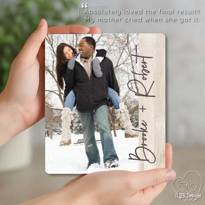 Hand holding a wooden photo plaque with a couple in the snow and personalized names.