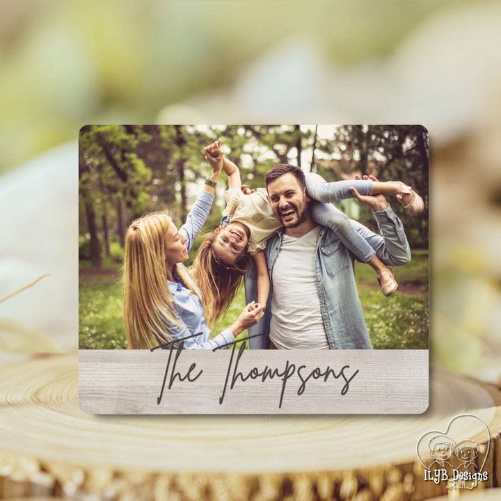 Family photo on a wooden plaque with 'The Thompsons' text, set against a blurred natural background.