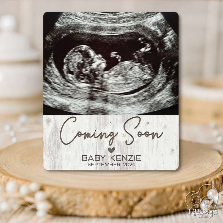Ultrasound image with 'Coming Soon' and baby name card on a wooden surface