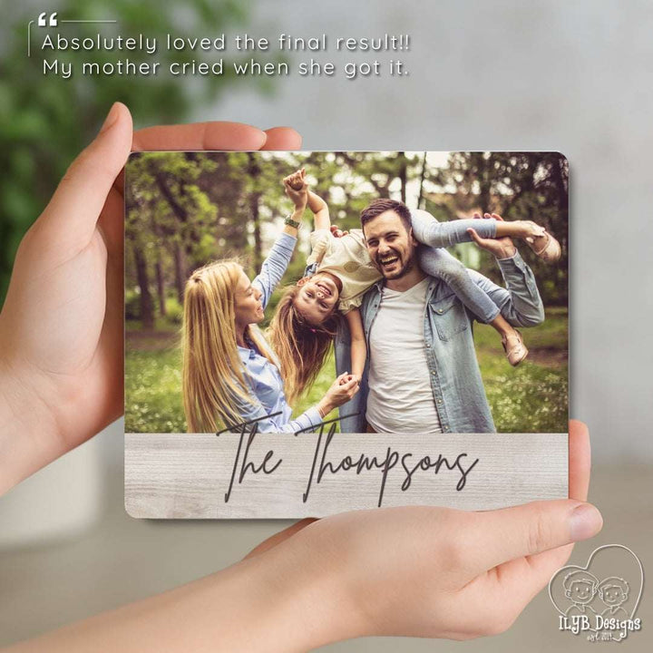 Person holding a photo plaque with a family picture and 'The Thompsons' text.