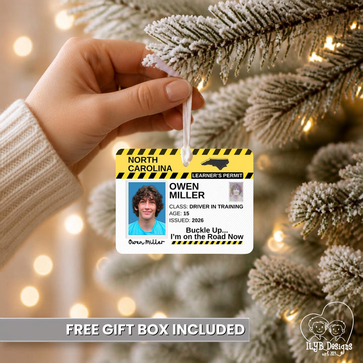 A hand holds a white ornament shaped like a North Carolina driver&
