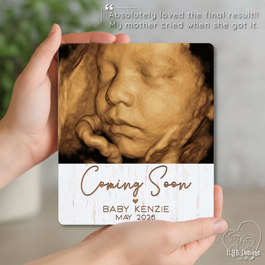 Hand holding a photo plaque with a baby ultrasound image and 'Coming Soon' text.