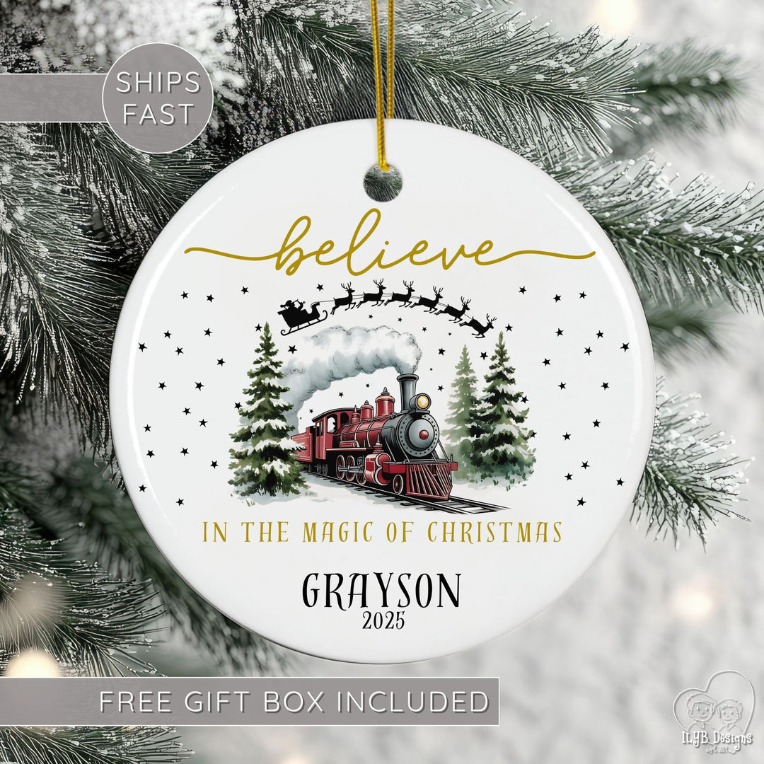 Christmas ornament with a train design and text 'believe in the magic of Christmas Grayson 2025' on a tree.