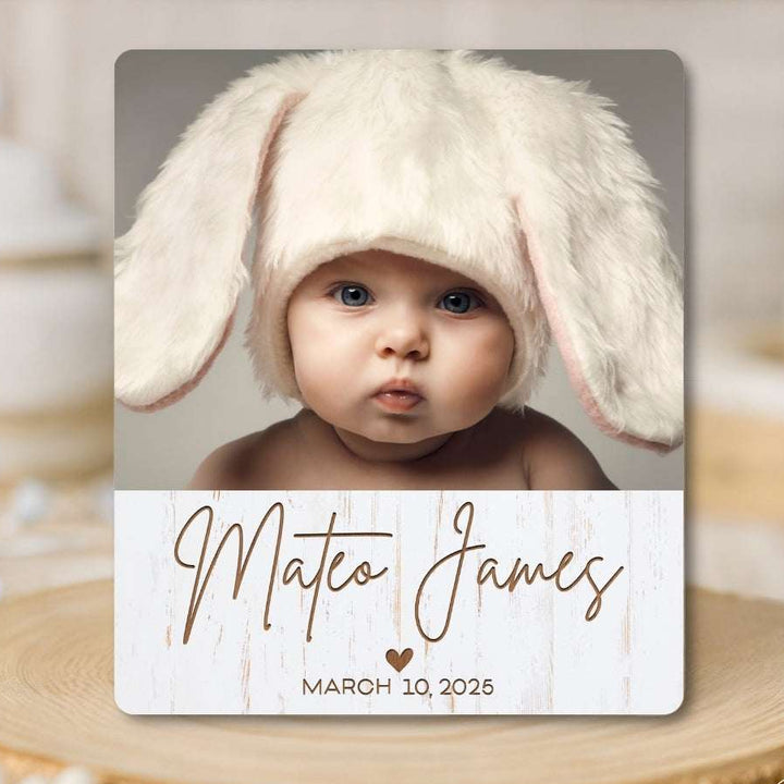 Baby wearing a bunny hat with a nameplate on a wooden surface