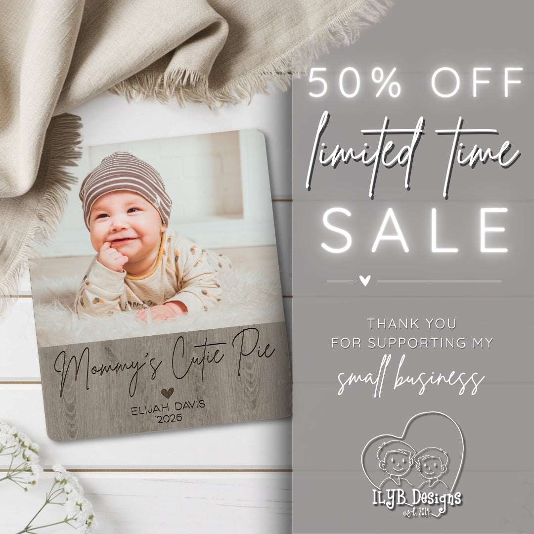 Personalized photo plaque with a baby's photo and text, placed on a wooden surface with a blanket and flowers.