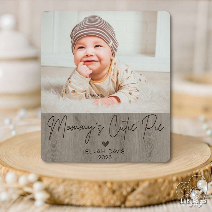 Personalized photo plaque with a baby's photo and text on a wooden surface.