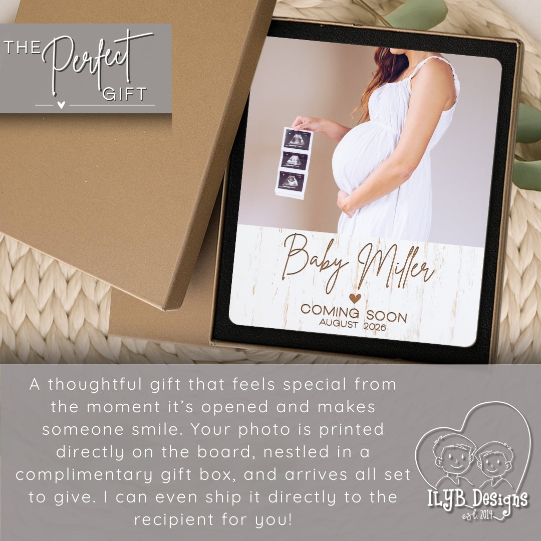 Pregnant woman holding a baby announcement photo board with 'The Perfect Gift' branding.