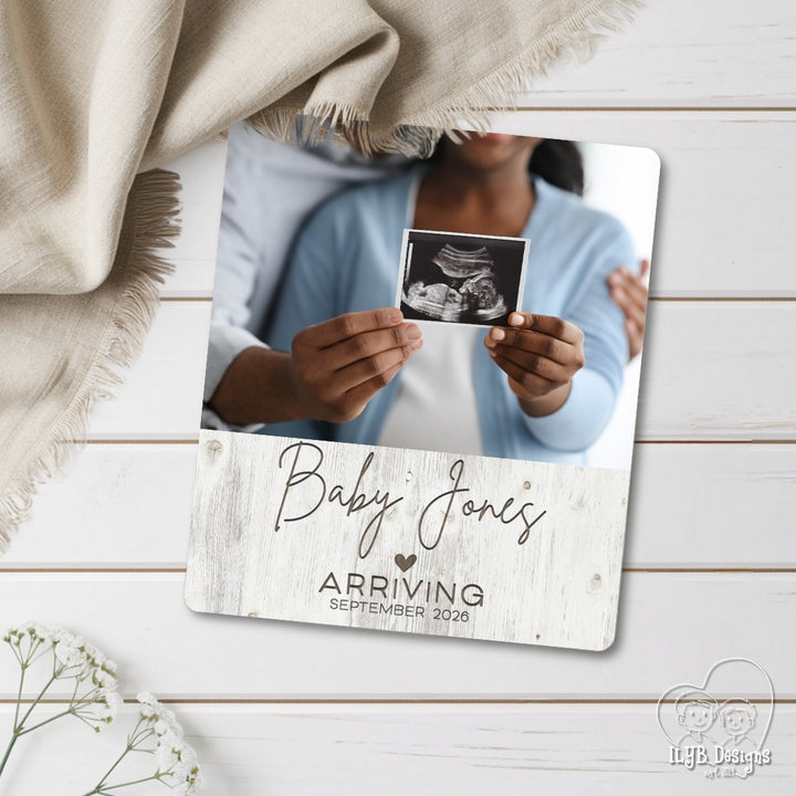 Personalized baby announcement photo board with ultrasound photo on a wooden surface.