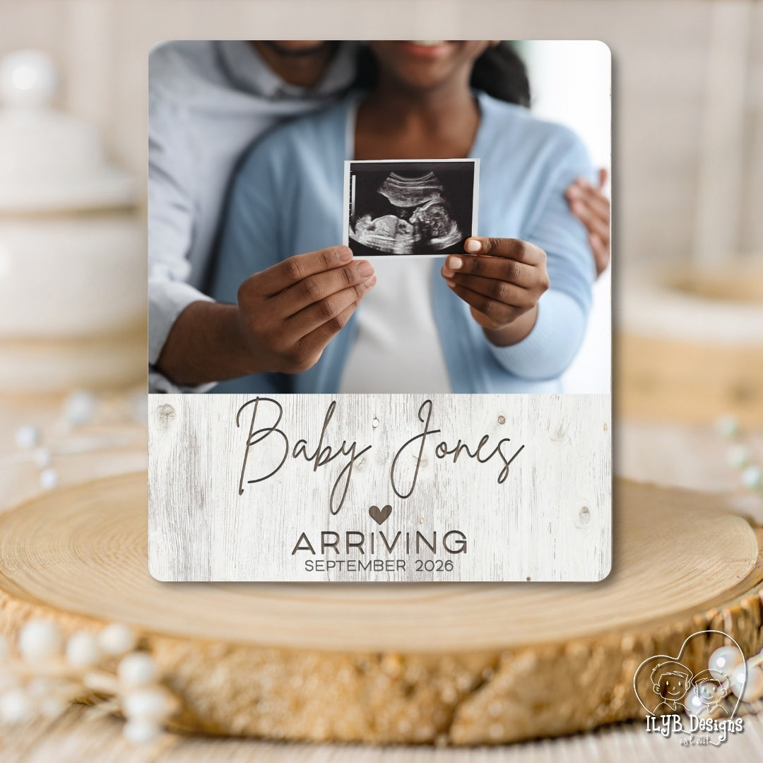 Baby announcement photo board with ultrasound photo and 'Baby Jones' text on a wooden surface.