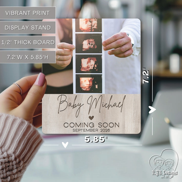 Baby announcement photo board held by a hand with dimensions displayed