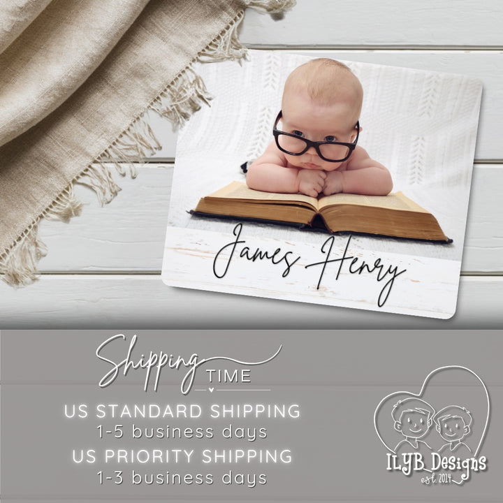 Baby lying on an open book with glasses, surrounded by a blanket on a wooden surface, with text about shipping time and a brand logo at the bottom.