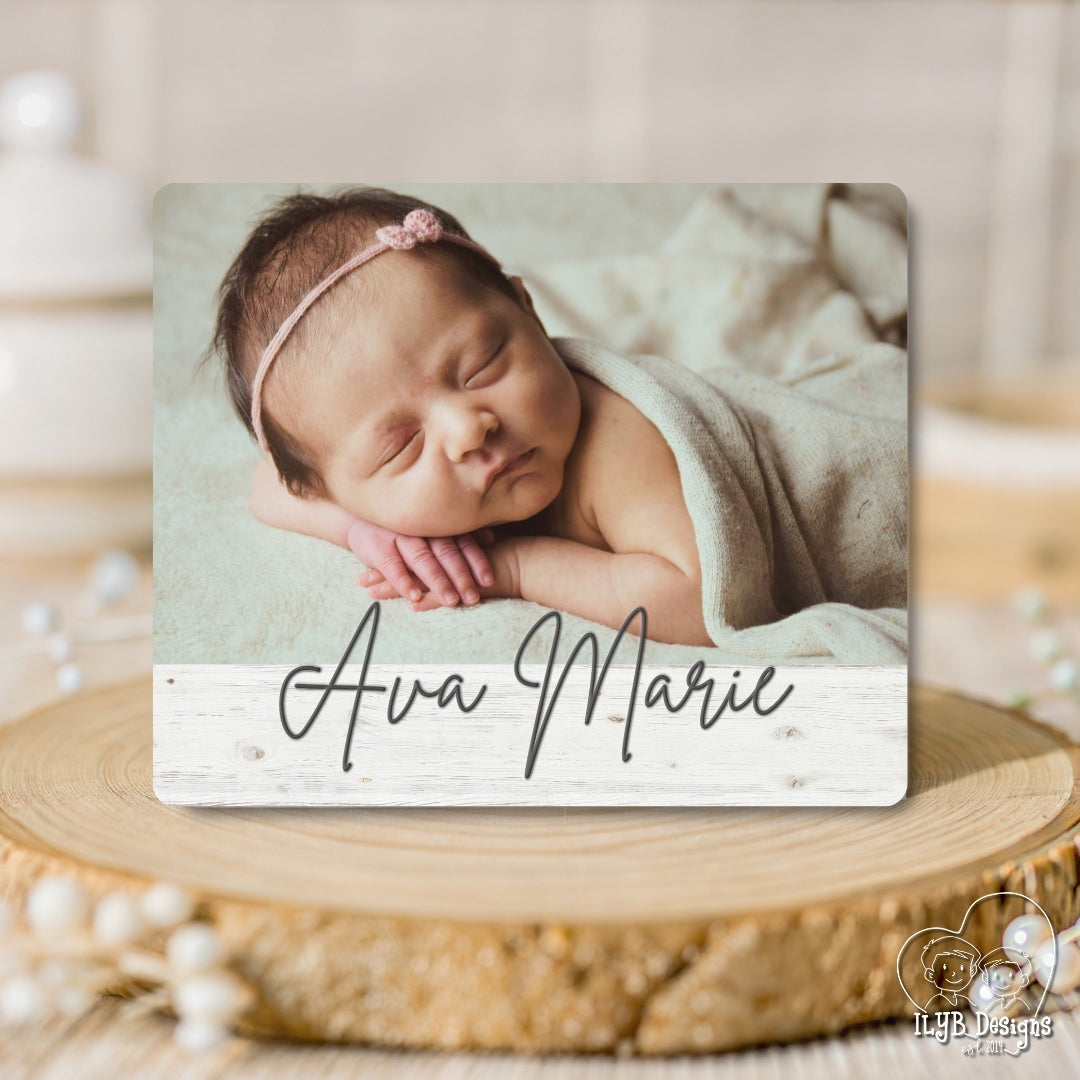 Newborn baby photo with 'Ava Marie' text on a wooden surface