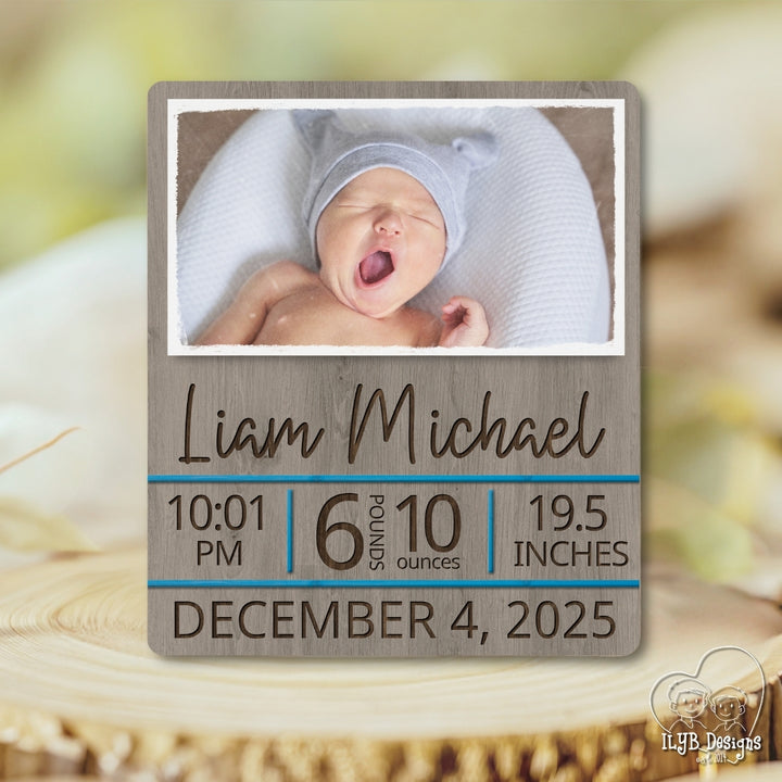 Wooden plaque with baby photo and birth details on a blurred natural background