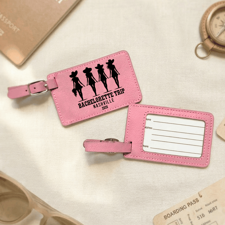 Pink luggage tag with 'Bachelorette Trip Nashville' design on a light surface with travel items.