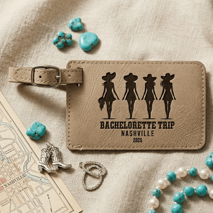 Light brown faux leather luggage tag with 'Bachelorette Trip Nashville 2026' design on a textured surface with decorative items.