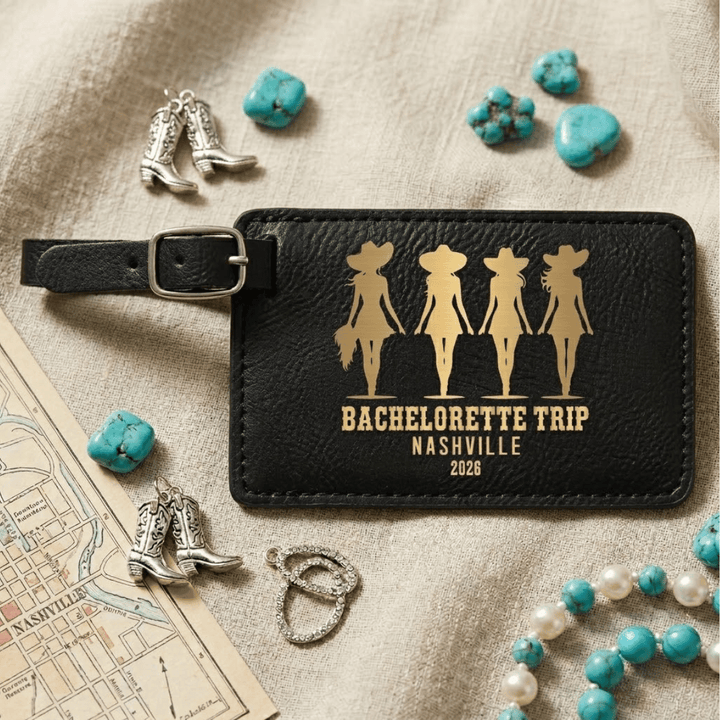 Black leather luggage tag with 'Bachelorette Trip Nashville 2028' design, surrounded by decorative items on a textured surface.