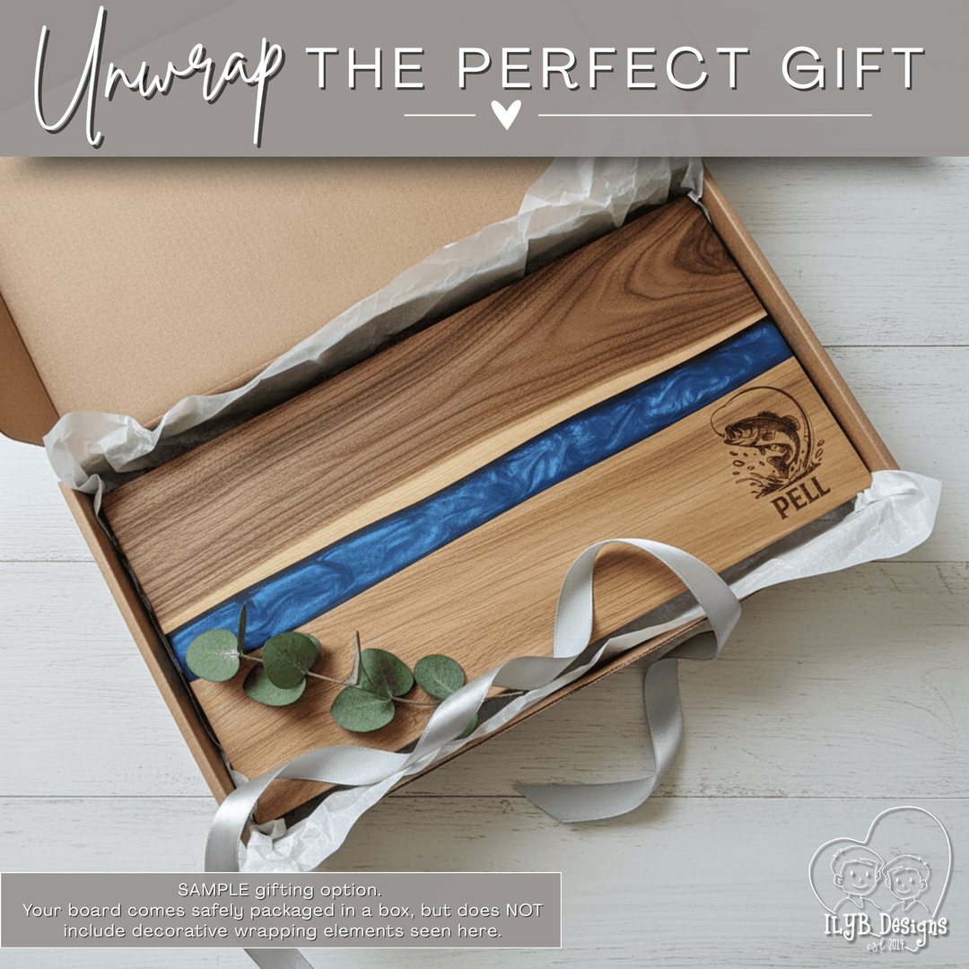 Wooden cutting board with blue inlay and name 'PELL' engraved in bottom right corner in a gift box on a light wooden surface.