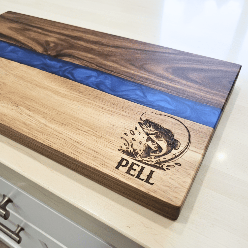 Wooden cutting board with blue resin strip and engraved fish design on a white surface