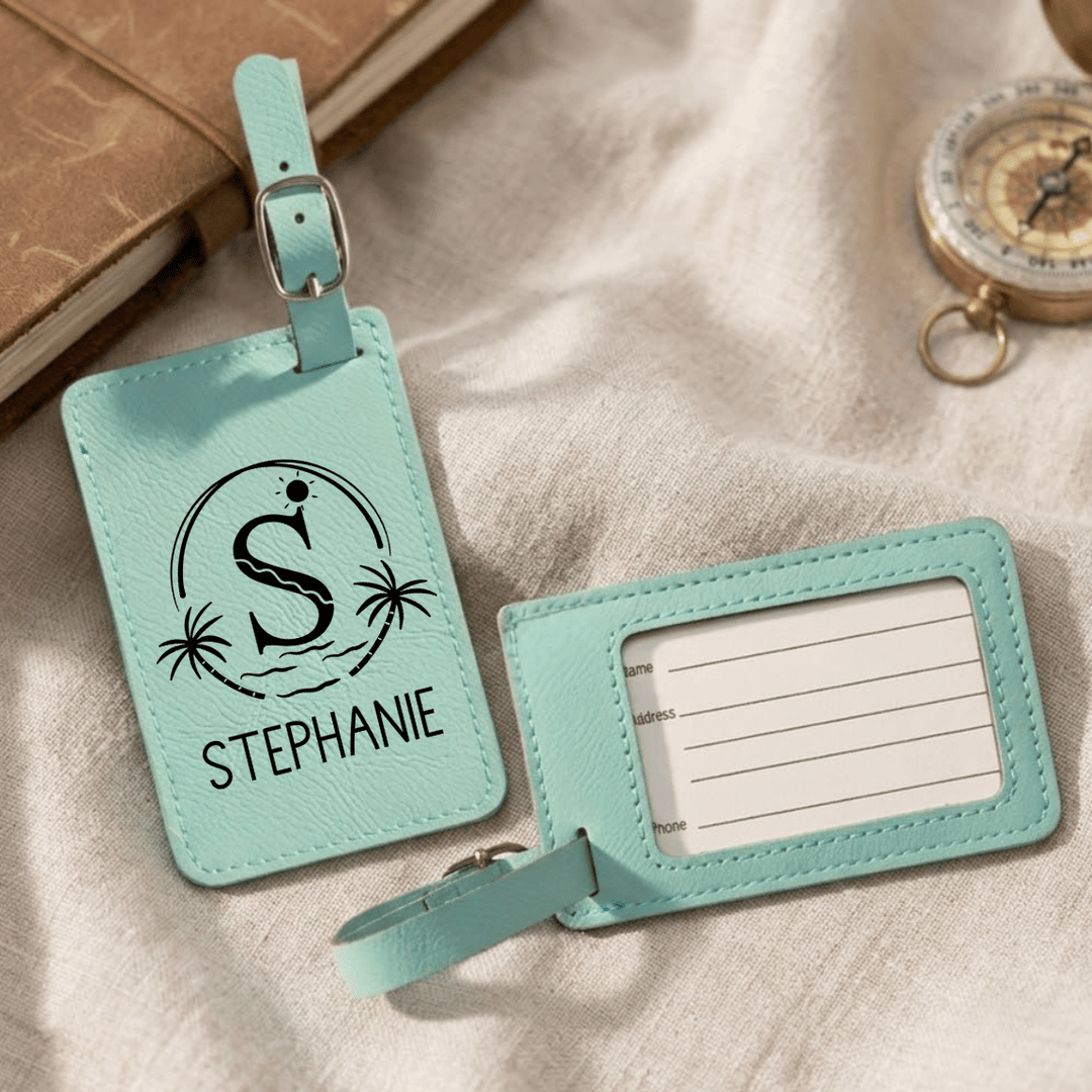 Front and back of teal luggage tags with a personalized design engraved on front side and clear plastic on back with blank tag inside for personal information.
