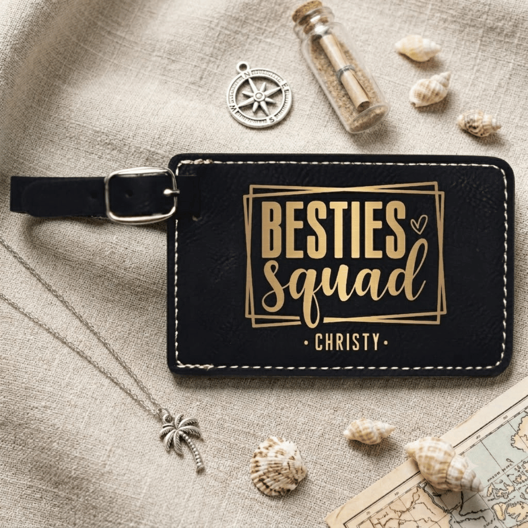 Black luggage tag with 'Besties Squad' text on a textured surface with decorative items.