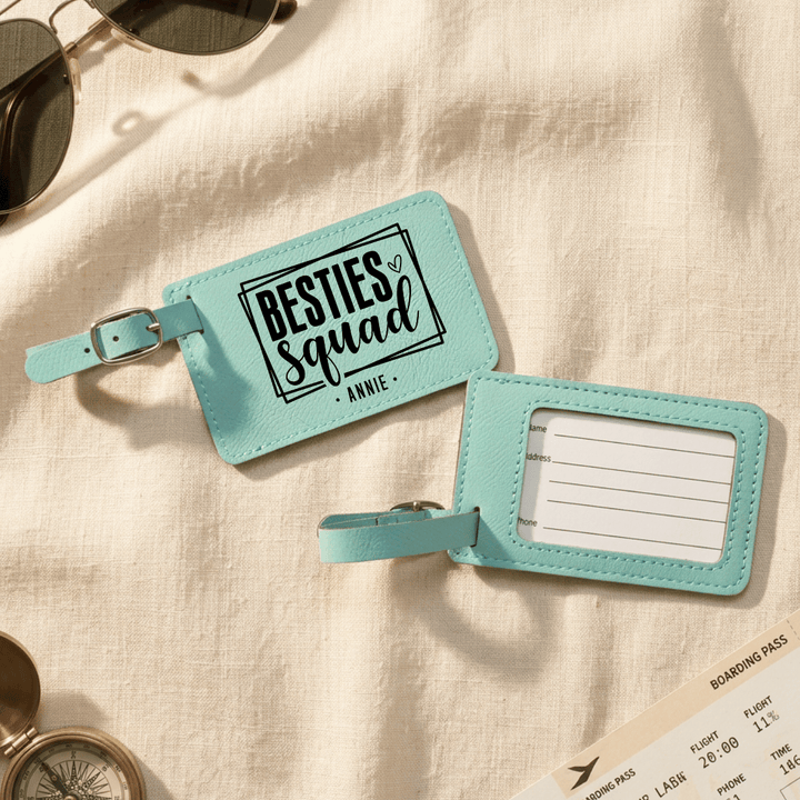 Teal luggage tag with 'besties squad Annie' engraved in black on the front and the back has clear plastic opening with space to write personal information.