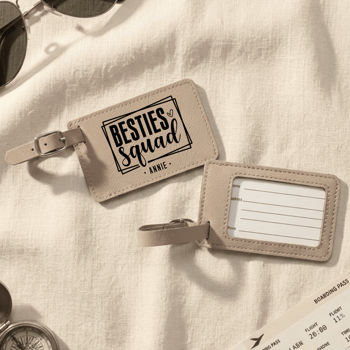 Light brown luggage tag with 'besties squad Annie' engraved in black on the front and the back has clear plastic opening with space to write personal information.